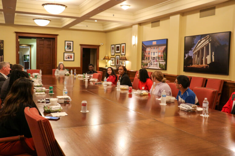 Group of students gather around table to listen to Dr. Cook