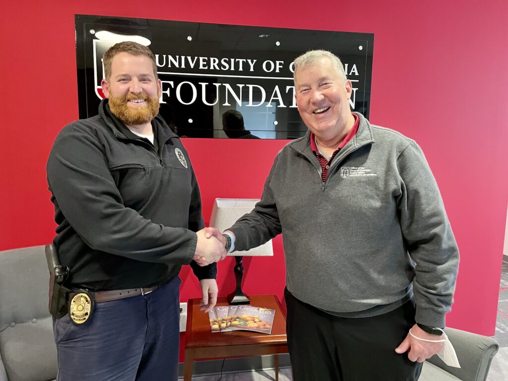 Major Adam Fouche shakes hands with Dean of Students, Bill McDonald, after receiving UGAPD donation.