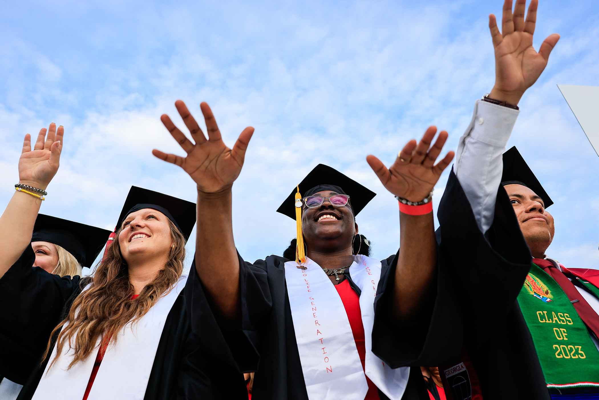 Three students outside on graduation.
