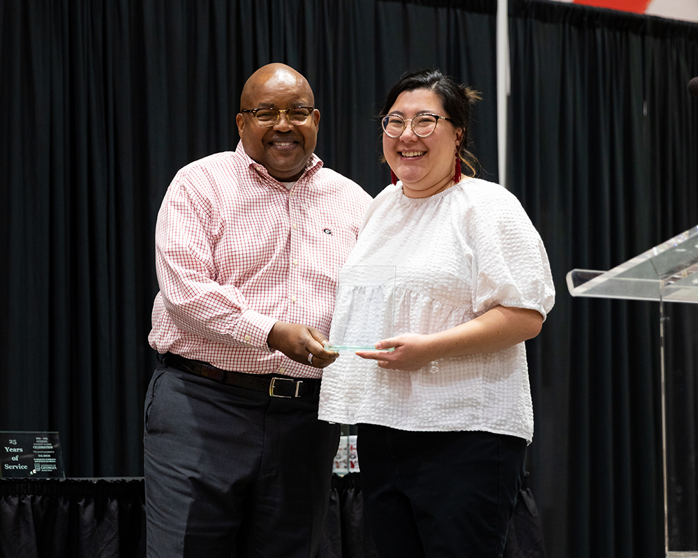 Two people with one of them holding an award.