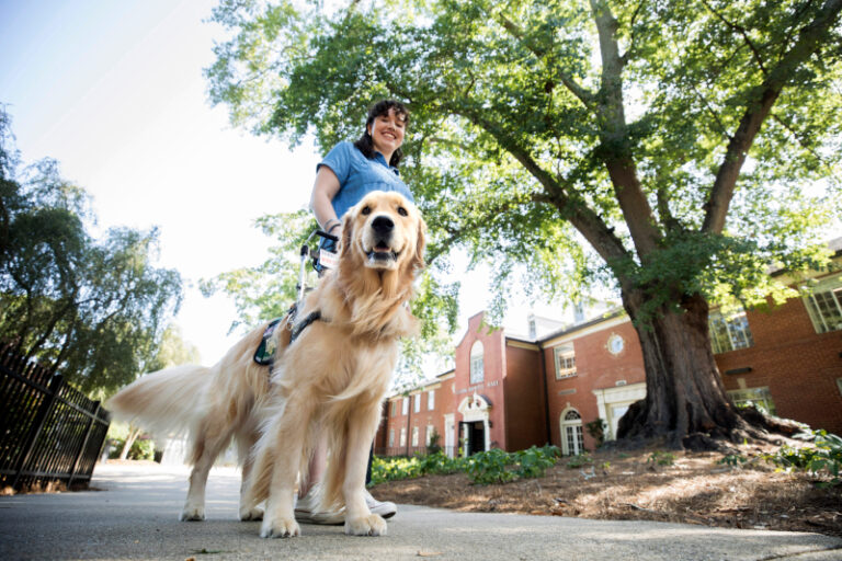 Girl and Golden Retriever smiling standing outside of Clark Howell Hall