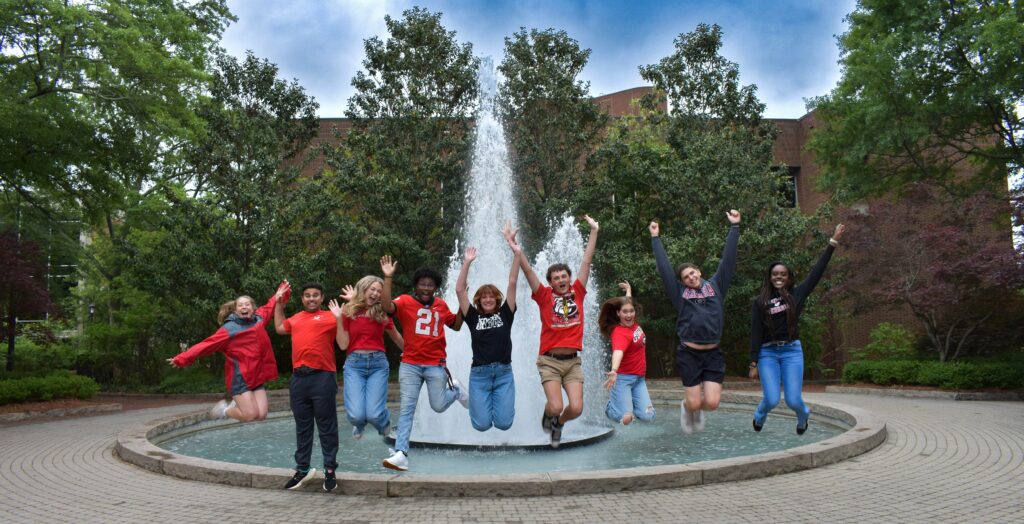 Students jumping in air in front of Herty Fountain