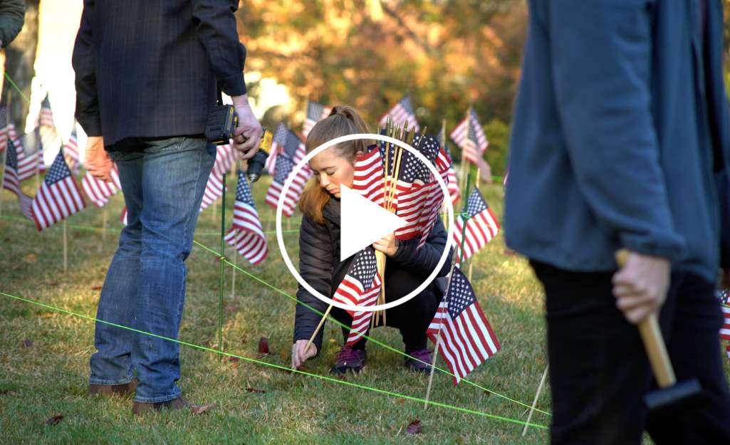 Female student veteran placing flag in the ground