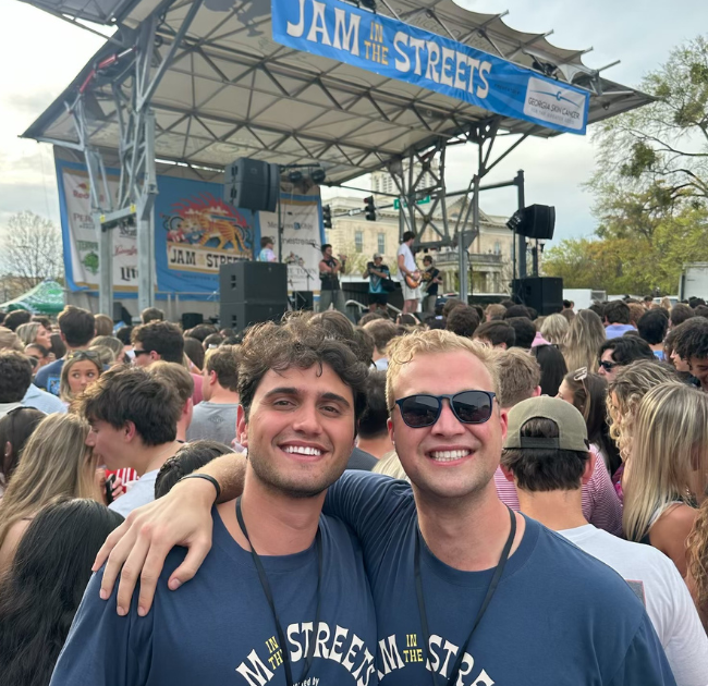 Briggs Settlemier and Dimitri Nakis smile side-by-side in front of stage