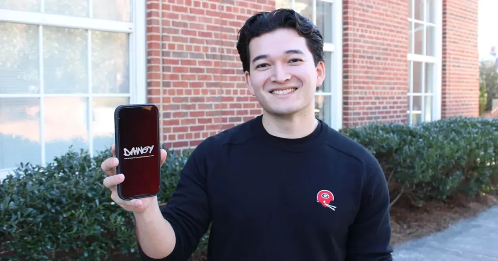 Student holding up phone with dawgy app on it.