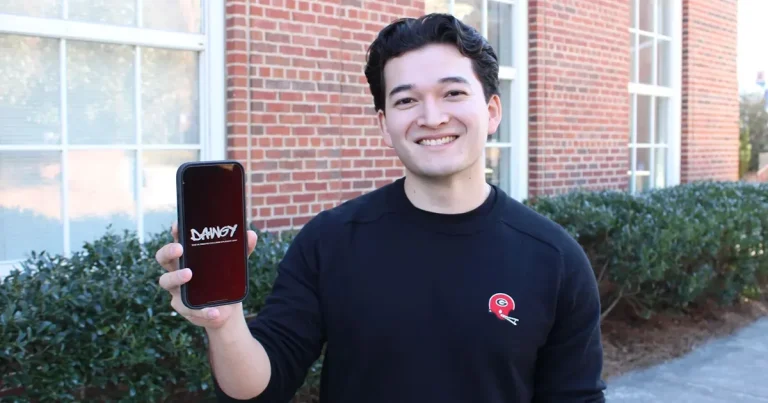 Student holding up phone with dawgy app on it.