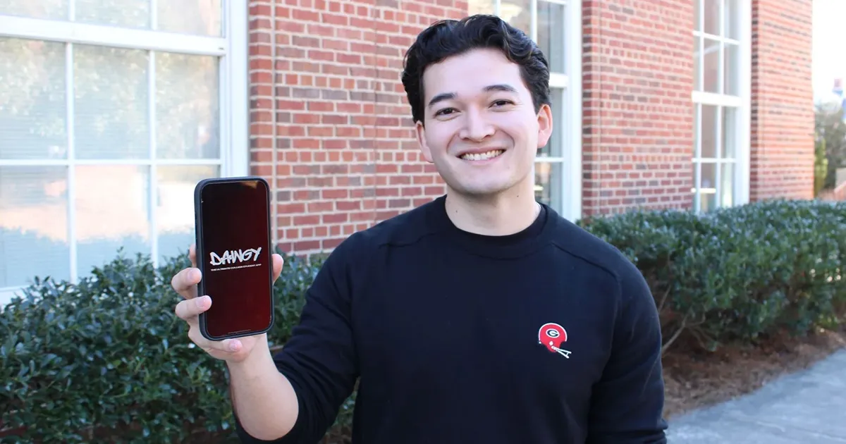 Student holding up phone with dawgy app on it.