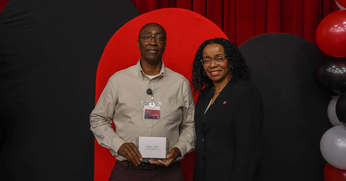 Vice President Michelle Cook (left) smiling with Donnie Smith (right), who is holding his Years of Service award. 